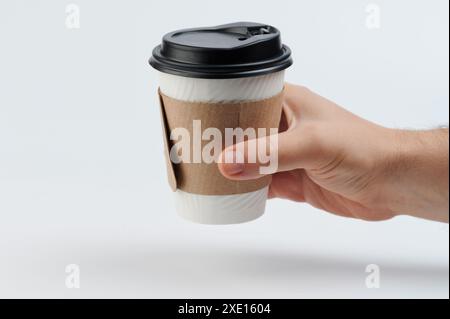 Paper cup with plastic lid in hand side view isolated on white studio background Stock Photo