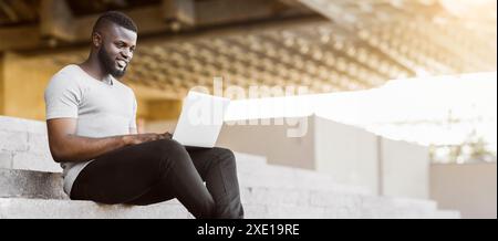Smiling african american guy coding on his laptop Stock Photo