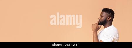 Man Thinking in Profile Against a Peach Background Stock Photo