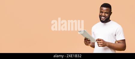 Smiling Man Using Tablet in Front of a Peach Background Stock Photo