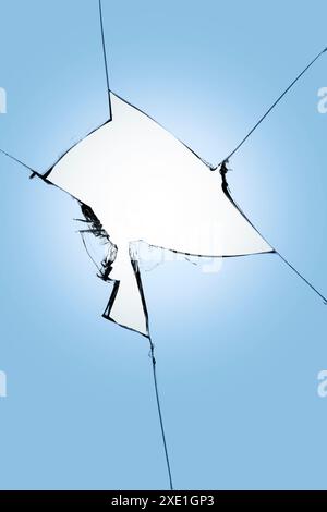 Broken glass on a blue background, cracks in the glass, abstract background with a hole in the center. Stock Photo