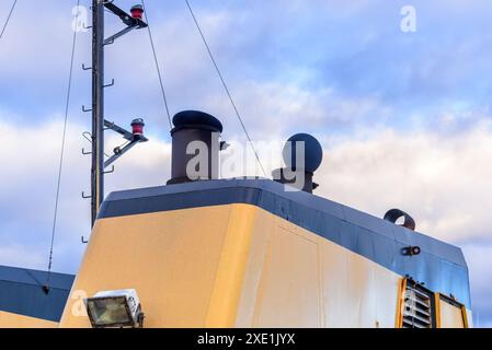 Smoke belching out from a funnel of a ferry in navigation under cloudy sky at dusk Stock Photo