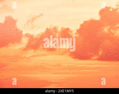 Raindrops on glass window over sunset sky Stock Photo