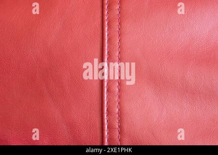 A close-up view of a red leather, highlighting its rich texture and the meticulous stitch work that runs down its spine and a vibrant red hue exudes l Stock Photo