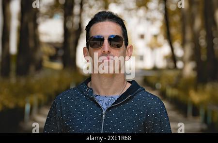 Mediterranean man in casual sports clothing and sunglasses, front portrait, focused attitude. Stock Photo