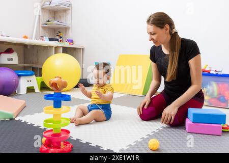 Paediatric physiotherapy treatment. Physiotherapist works with a young child on motor skills development in a rehabilitation center Stock Photo