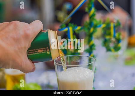 Close-up of man's hand pouring beer from can into a glass at festive table. Stock Photo