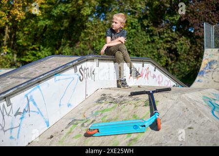 Child on kick scooter in park. Kids learn to skate roller board. Little boy skating on sunny summer day. Outdoor activity for ch Stock Photo