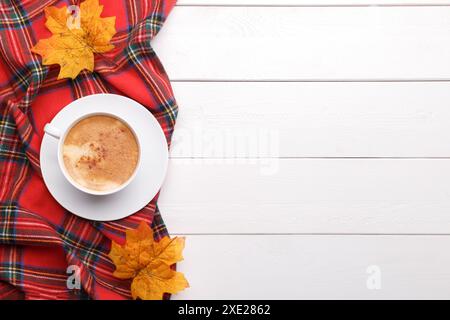 Cup of coffee on checkered blanket with autumn leafs and pumpkins copy space white wooden background Stock Photo