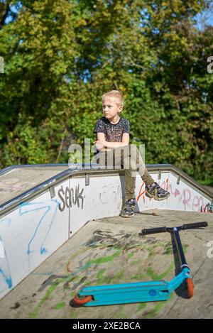 Child on kick scooter in park. Kids learn to skate roller board. Little boy skating on sunny summer day. Outdoor activity for ch Stock Photo