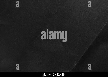 Black paper textured surface with a subtle fold and unique natural pattern. Dark cardboard tones create a sense of abstract depth and mystery Stock Photo