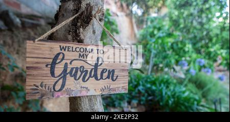 Garden welcome sign with mediterranean courtyard as background. English language letters Stock Photo