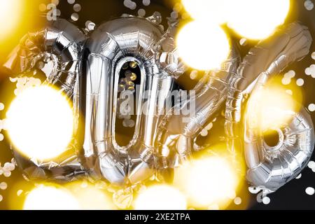 Holiday bokeh garland Happy new year 2026 metallic balloons with confetti on dark black background. Greeting card silver foil ba Stock Photo