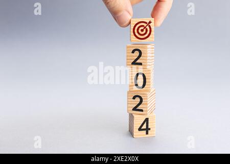 Hand holding a target icon on top of Wooden blocks with 2024 number. 2024 business goal concept. Copy space Stock Photo