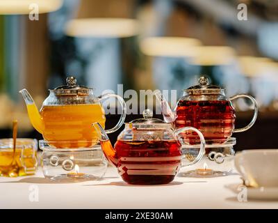Set of three glass teapots with warmer on table Stock Photo