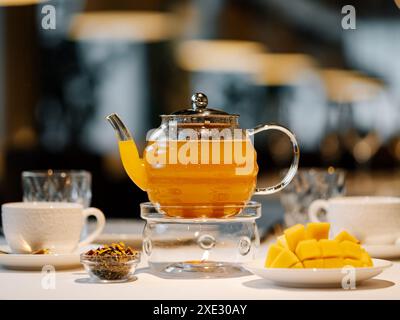 Mango herbal tea in teapot with warmer Stock Photo