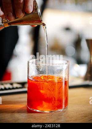 Bartender making Negroni cocktail on bar counter Stock Photo