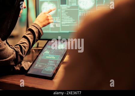Hackers gettng access to important database online on computer network, planting virus to create malware. Team of spies working on cyberterrorism attack with online script codes. Stock Photo