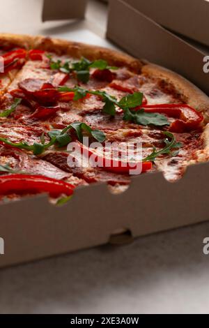 Large Pizza with pepperoni and bell peppers in open carton box closeup view Stock Photo