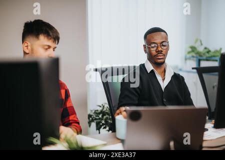 Diverse business team working at office desks, analyzing documents and using computers Stock Photo