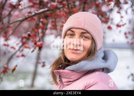 Winter lifestyle portrait of cheerful pretty girl. Smiling and having fun in the snow park. Snowflakes falling down. Stock Photo