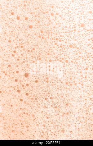 The texture of soap foam with bubbles on a Peach Fuzz background. Stock Photo