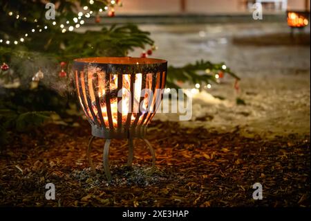 Fire pit with delightful bokeh of christmas lighting in background.Warm flames dance in the night wi Stock Photo