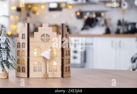 Key and tiny house of a small size on cozy home with Christmas decor on table of festive white kitchen. Gift for New Year. Insur Stock Photo