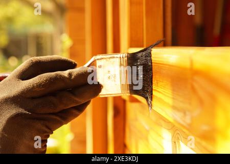 Lasurer. Painting woodwork outside. hand of Handyman varnishing a wooden door. Concept of renovation Stock Photo