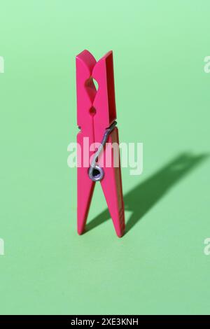 Pink colored plastic clothespin on green background.. Minimal concept art. Abstraction. Shadows. Stock Photo