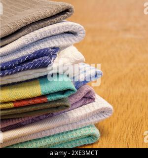 Pile of linen and cotton kitchen towels on a wooden table background. Stack of colorful dish towels Stock Photo