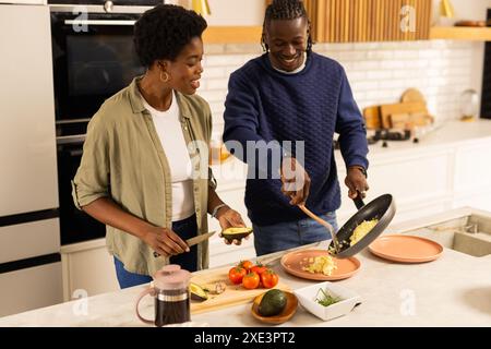 At home, Couple cooking breakfast together in modern kitchen, smiling and enjoying time Stock Photo
