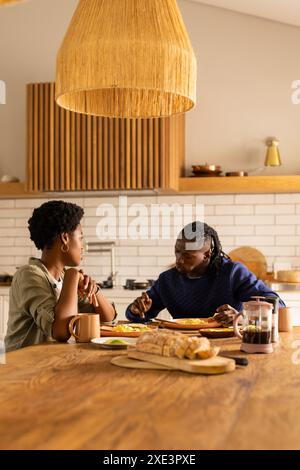 Couple enjoying breakfast together at home, sitting at wooden kitchen table Stock Photo