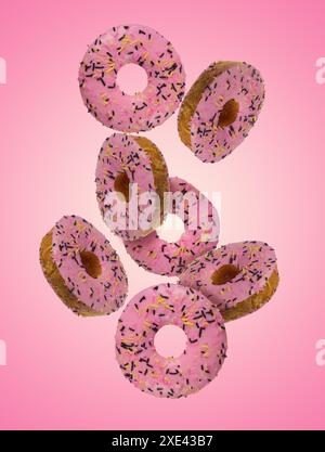 Donuts with pink glaze and sprinkled with colorful sprinkles levitate on a pink background Stock Photo