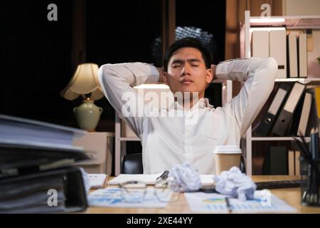 Young businessman working overtime on a desk at night.. Stock Photo