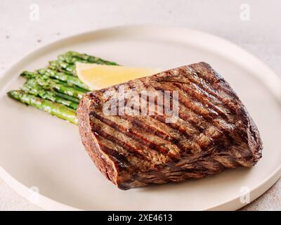 Grilled meat steak on plate with lemon and asparagus Stock Photo