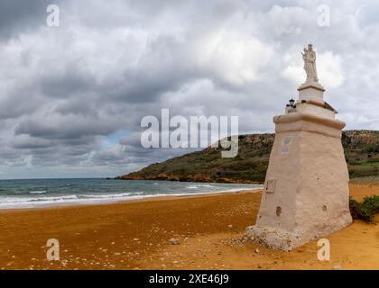 View of the red sand beach and Staue of Our Lady in Ramla Bay on Gozo Island in Malta Stock Photo