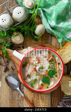 Traditional rustic thick german pea soup with smoked bacon, mushrooms and cereals on wooden table. Hot dinner or lunch. Stock Photo