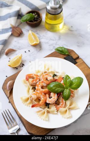 Mediterranean cuisine, seafood diet. Italian farfalle pasta with prawns garlic, basil and lemon on a marble tabletop. Stock Photo