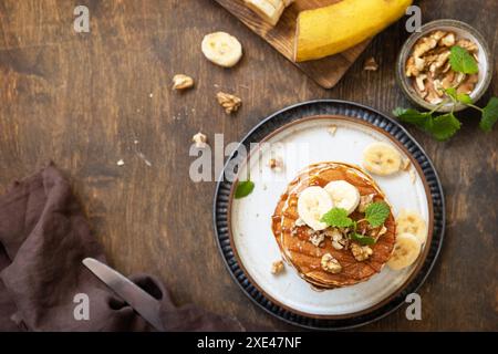 Celebrating Pancake day, american breakfast. Delicious homemade banana pancakes with nuts and caramel on rustic wooden table. To Stock Photo