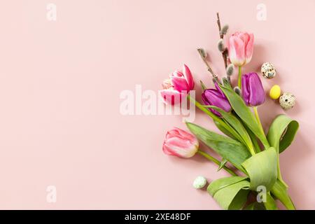 Easter composition with colorful Easter eggs and spring flowers tulips over pink background. Spring and Easter holiday concept. Stock Photo
