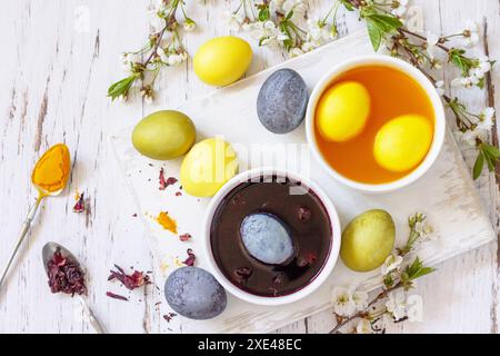 Natural dye for easter eggs, celebration Easter. Homemade colored easter eggs in carcade and turmeric on a rustic table. Top vie Stock Photo