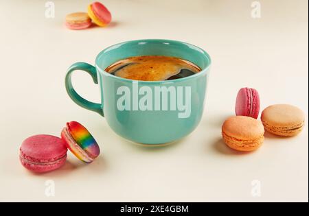 Multi-colored macaroons of different colors and flavors on a beige background with a cup of coffee. Stock Photo