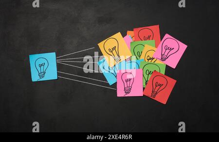 Drawn electric lightbulbs on paper sheets, signifying the concept of searching for new ideas. Stock Photo