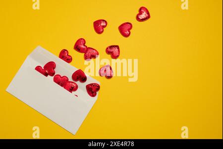 Rectangular white paper envelope and red hearts on a yellow background Stock Photo