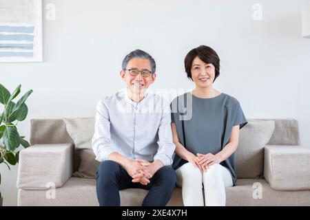 Senior couple sitting on a sofa and smiling Stock Photo