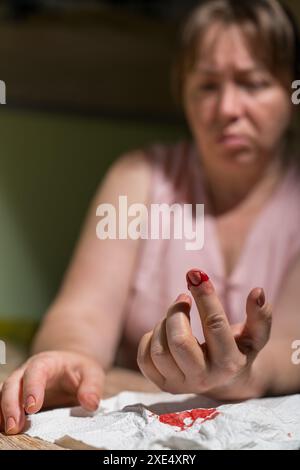 The woman cut her finger. Blood is flowing from the wound. Stock Photo