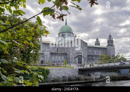 People walking along the River Corrib with the cathedral in the background Stock Photo