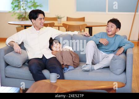 Father and two boys relaxing on sofa Stock Photo