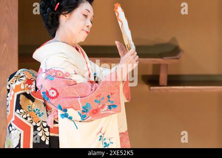 Elderly Japanese woman in kimono with fan dancing Japanese dance Stock Photo